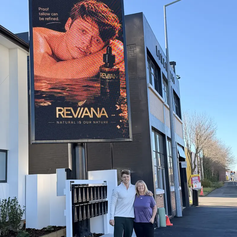 Curtis and a family member below the Reviana billboard